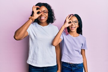 Beautiful african american mother and daughter wearing casual clothes and glasses doing ok gesture with hand smiling, eye looking through fingers with happy face.