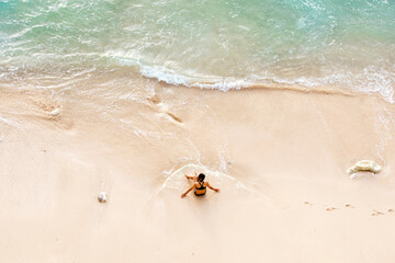 Girl in a swimsuit alone on the beach of the ocean. Top view, photo from a drone.