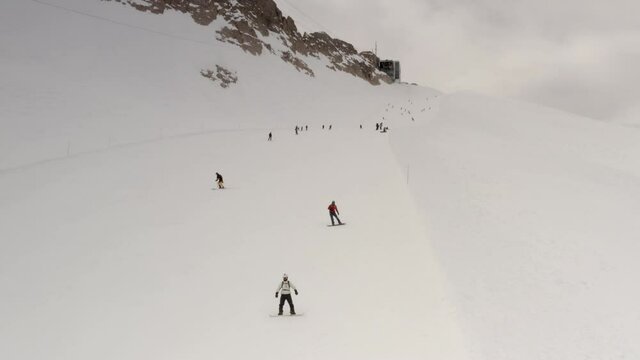 Aerial view of  People Skiing and snowboarding on hill, Ski Resort.
Drone flies over Skiers Skiing down the hill, Alp mountains, Dolmites Italy
