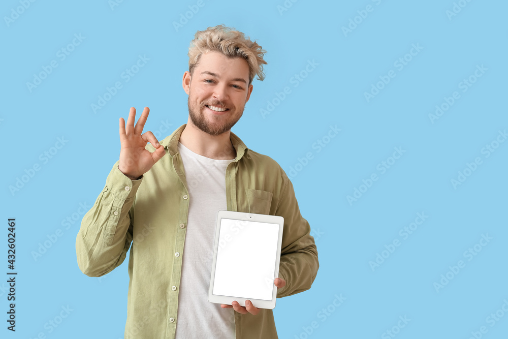 Poster young man with tablet computer showing ok on color background