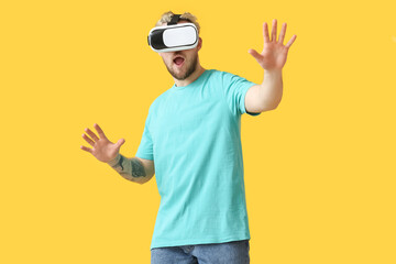Young man with VR glasses on color background