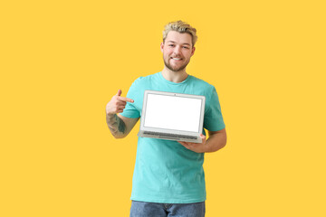 Young man with laptop on color background