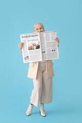 Mature woman with newspaper on color background