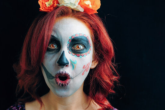 A young woman in day of the dead mask skull face art. Woman with Halloween skull make up over black background.