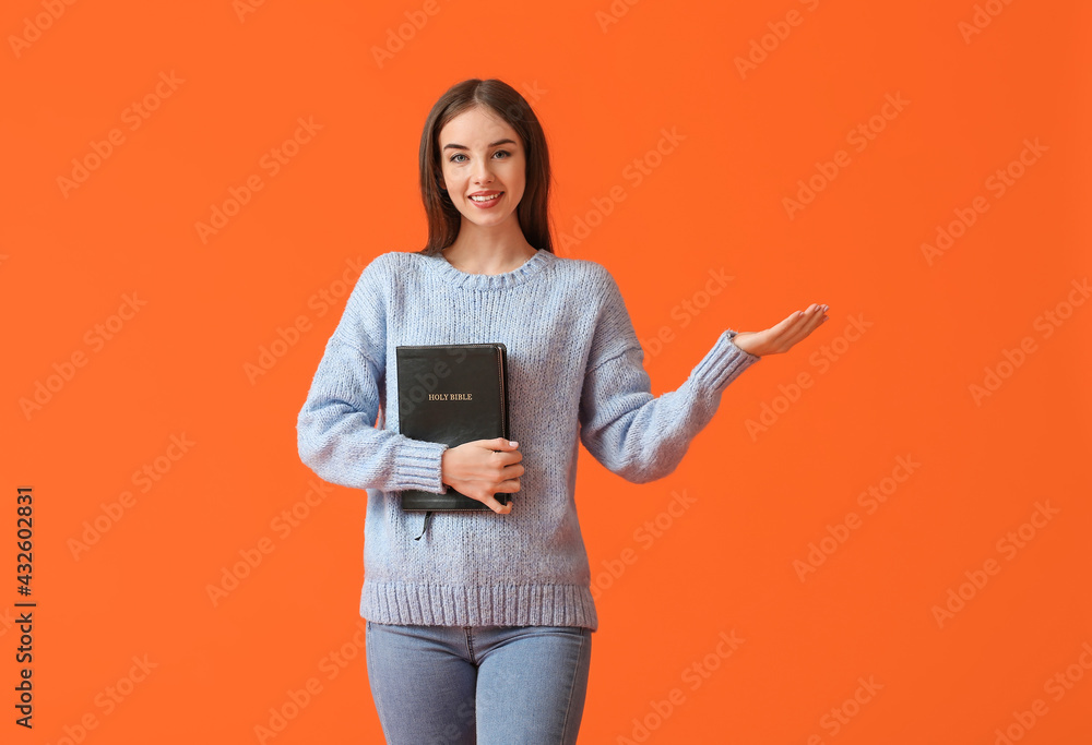 Wall mural young woman with bible on color background