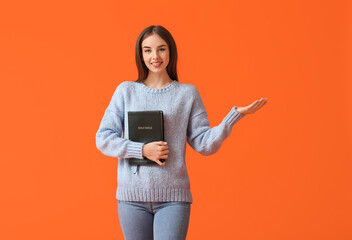 Young woman with Bible on color background