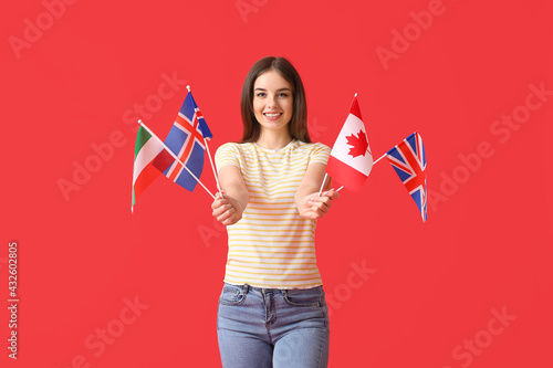 Beautiful young woman with different flags on color background