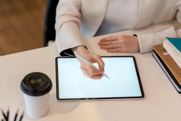 Close up of a businesswoman hand with a pen working on a tablet at the office.