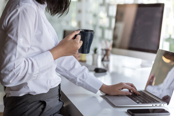 Close up of a businesswoman with a coffee cup ready to work on a tablet at a modern office.