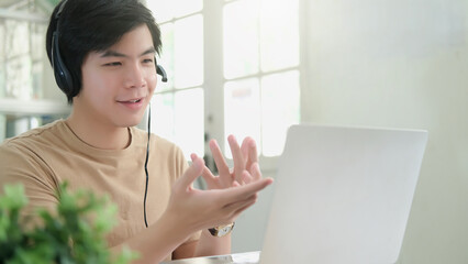 Student wearing headphones using laptop studying at home, making research on laptop and browse internet, watching online webinar, listening audio course, e-learning education concept