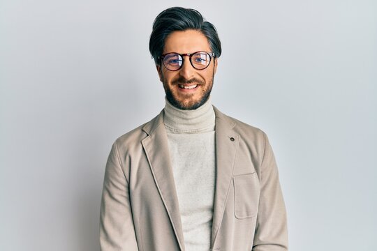 Young hispanic man wearing business jacket and glasses with a happy and cool smile on face. lucky person.