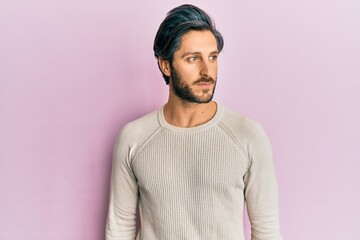Young hispanic man wearing casual winter sweater smiling looking to the side and staring away thinking.