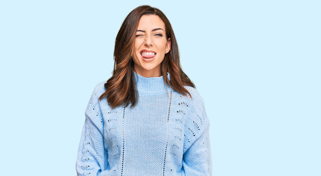 Young brunette woman wearing casual winter sweater sticking tongue out happy with funny expression. emotion concept.