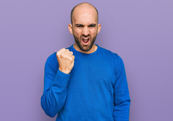 Fototapeta premium Young hispanic man wearing casual clothes angry and mad raising fist frustrated and furious while shouting with anger. rage and aggressive concept.