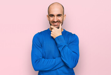 Young hispanic man wearing casual clothes looking confident at the camera smiling with crossed arms and hand raised on chin. thinking positive.