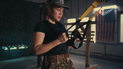 Obraz na płótnie Canvas Sweaty female soldier exercising in gym