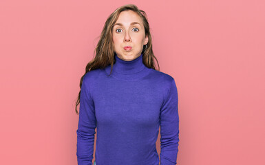Young blonde woman wearing casual clothes puffing cheeks with funny face. mouth inflated with air,...