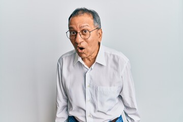 Middle age indian man wearing casual clothes and glasses afraid and shocked with surprise expression, fear and excited face.