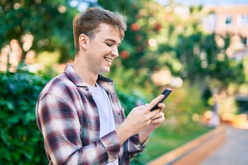 Young caucasian man smiling happy using smartphone at the park.