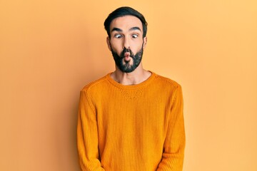 Fototapeta premium Young hispanic man wearing casual clothes making fish face with lips, crazy and comical gesture. funny expression.