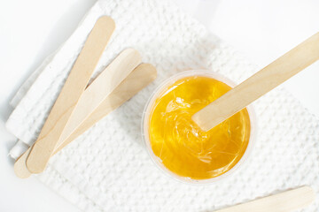 Sugar paste or wax honey in a transparent jar on a white background. Sugaring. Depilation and beauty concept. Waxing.