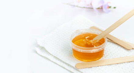 Sugar paste or wax honey in a transparent jar on a white background. Sugaring. Depilation. Epilation.