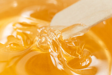 Sugar paste or wax honey in a transparent jar on a white background. Sugaring. Depilation and beauty concept. Waxing.