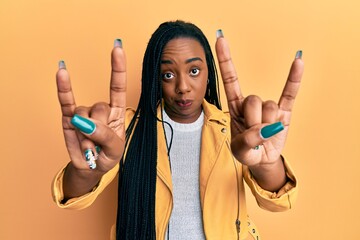 Young african american woman doing rock gesture skeptic and nervous, frowning upset because of...
