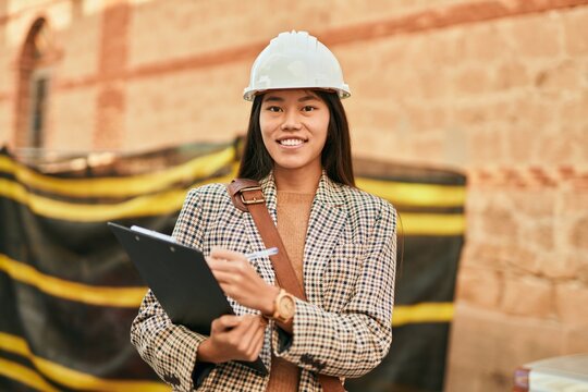 Young asian architect woman smiling happy writing on clipboard at the city.