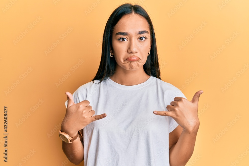 Sticker Young asian woman doing shaka sign with hands depressed and worry for distress, crying angry and afraid. sad expression.