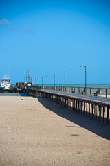 Obraz premium Wooden pier on a sandy beach that leads to a jetty in the city of Riohacha. Colombia.