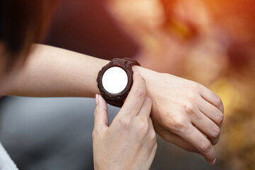 close up wristwatch with white dial in hand of woman. female checking smartwatch.