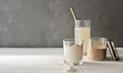 whey protein drink in a glass and jars with protein powder on beige background. chocolate and vanilla supplement for healty lifestyle, copy space.