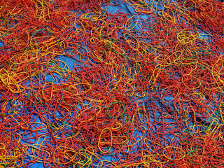 Freshly made rubber bands of different colors being sun dried, spread on the ground.