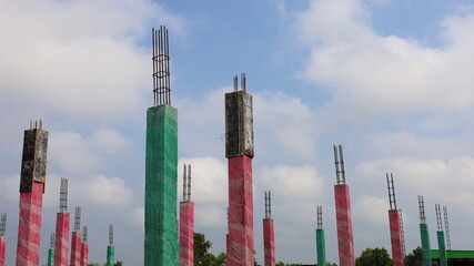 Curing cement poles with plastic. Green and pink plastic concrete columns are wrapped to control the moisture in the posts and complete the hydration for high durability. Close focus on the subject