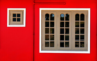 Red wall with two windows with white frame.