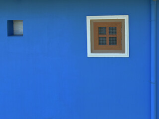 Blue wall and a small window with white frame.