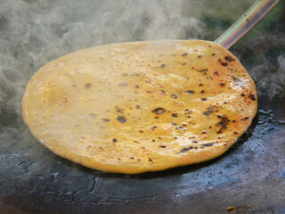 Affordable food. Eating out in Delhi. Roadside eatery. Making of hot, ready to eat ghee-coated...