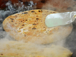 Affordable food. Eating out in Delhi. Roadside eatery. Making of hot, ready to eat ghee-coated tandoori roti chapati for customers who eat on the spot.