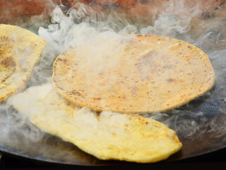 Affordable food. Eating out in Delhi. Roadside eatery. Making of hot, ready to eat ghee-coated tandoori roti chapati for customers who eat on the spot.