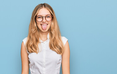 Beautiful young caucasian girl wearing casual clothes and glasses sticking tongue out happy with funny expression. emotion concept.