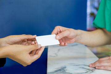 Close up woman hands reciving white plastic card. - obrazy, fototapety, plakaty