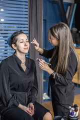 Woman make up master applying skin tone foundation powder blush on face use brush at beauty salon
