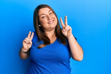 Beautiful brunette plus size woman wearing casual blue t shirt smiling looking to the camera...