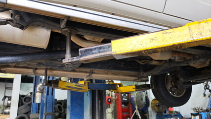 Fototapeta premium Lifting pad of the car lift in the garage. Car with lift service in the car repair center in the bottom view. Close focus on the subject