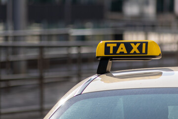 Taxi with yellow sign on roof on a shiny day waiting for passengers and tourists to drive to airport or home as flexible transportation in urban cities and streets on journeys and European mobility