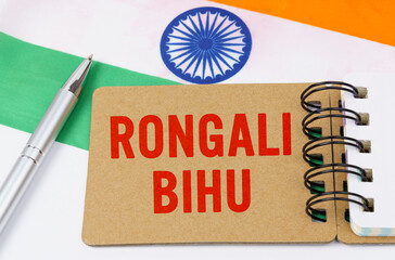Against the background of the flag of India lies cardboard with the inscription - Rongali Bihu