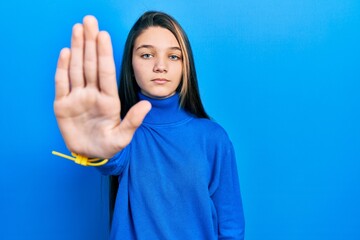 Young brunette girl wearing turtleneck sweater doing stop sing with palm of the hand. warning expression with negative and serious gesture on the face.