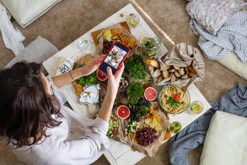 Top view woman photographing dinner table with serving tasty food and drink use smartphone