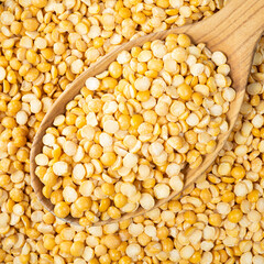 dried split yellow peas in wooden spoon closeup